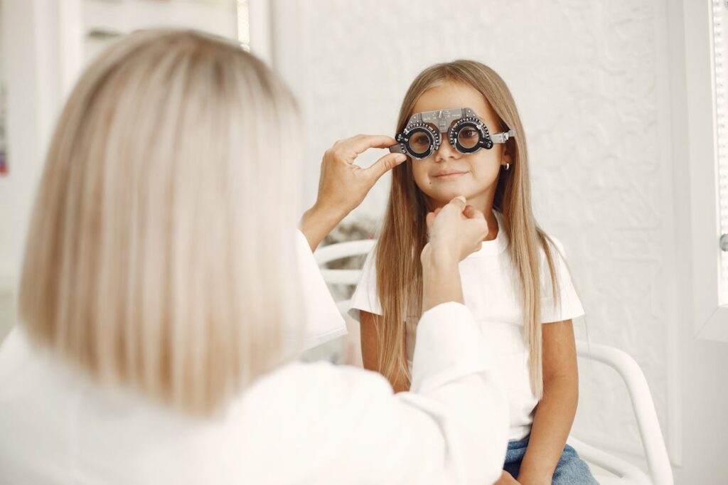 A young girl getting an eye exam at a healthcare clinic with optometrist assistance.