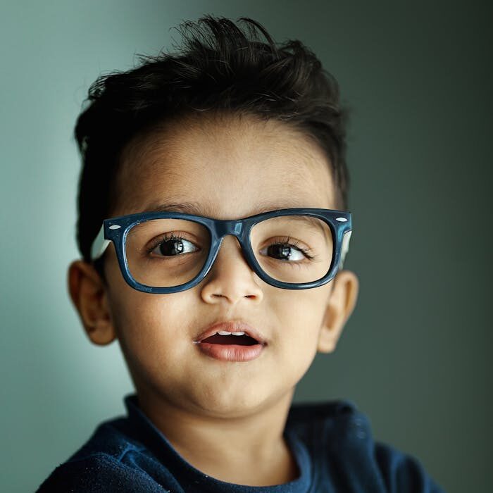 Charming portrait of a young boy with eyeglasses and a playful expression.